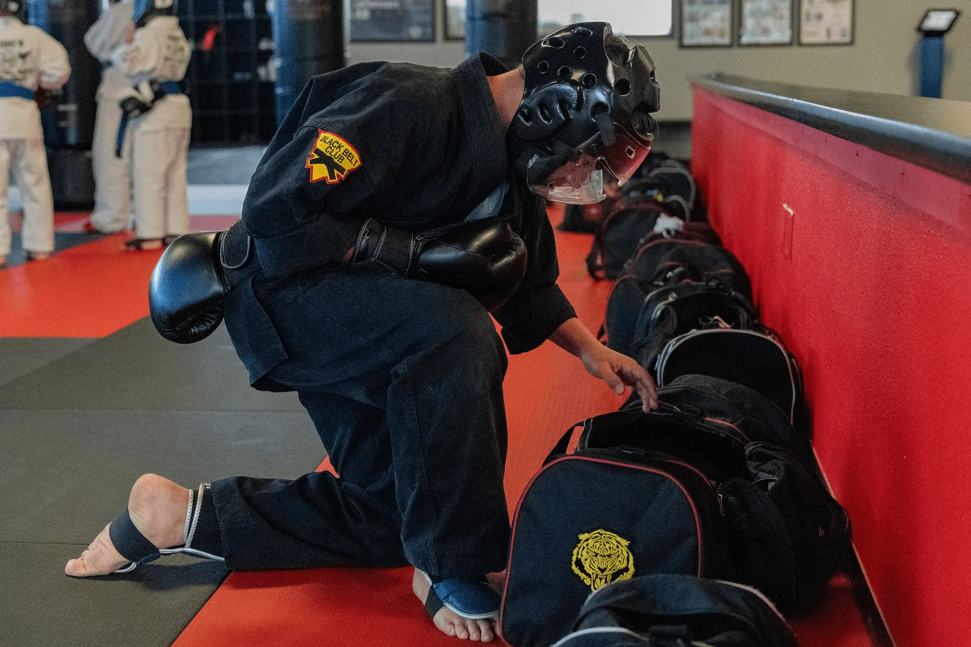 Junior MMA training gloves and focus pad on a wooden dojo floor at Guido's Martial Arts Academy in Clovis, CA