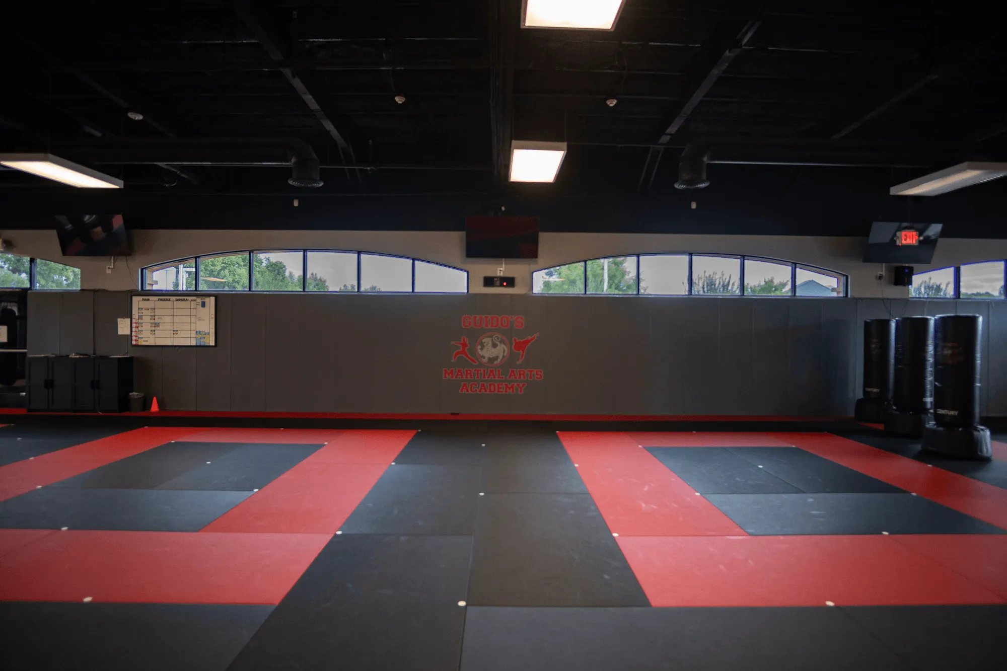 The edge of a blue BJJ training mat meeting hardwood at Guido's Martial Arts Academy in Clovis, CA