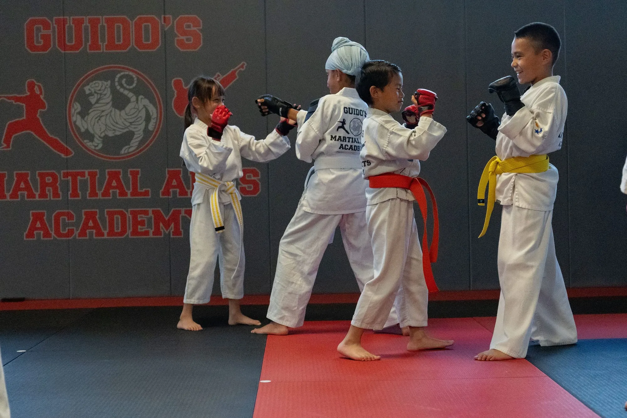 Two Juniors MMA students sparring with hand pads in white gi with purple belts at Guido's Martial Arts Academy