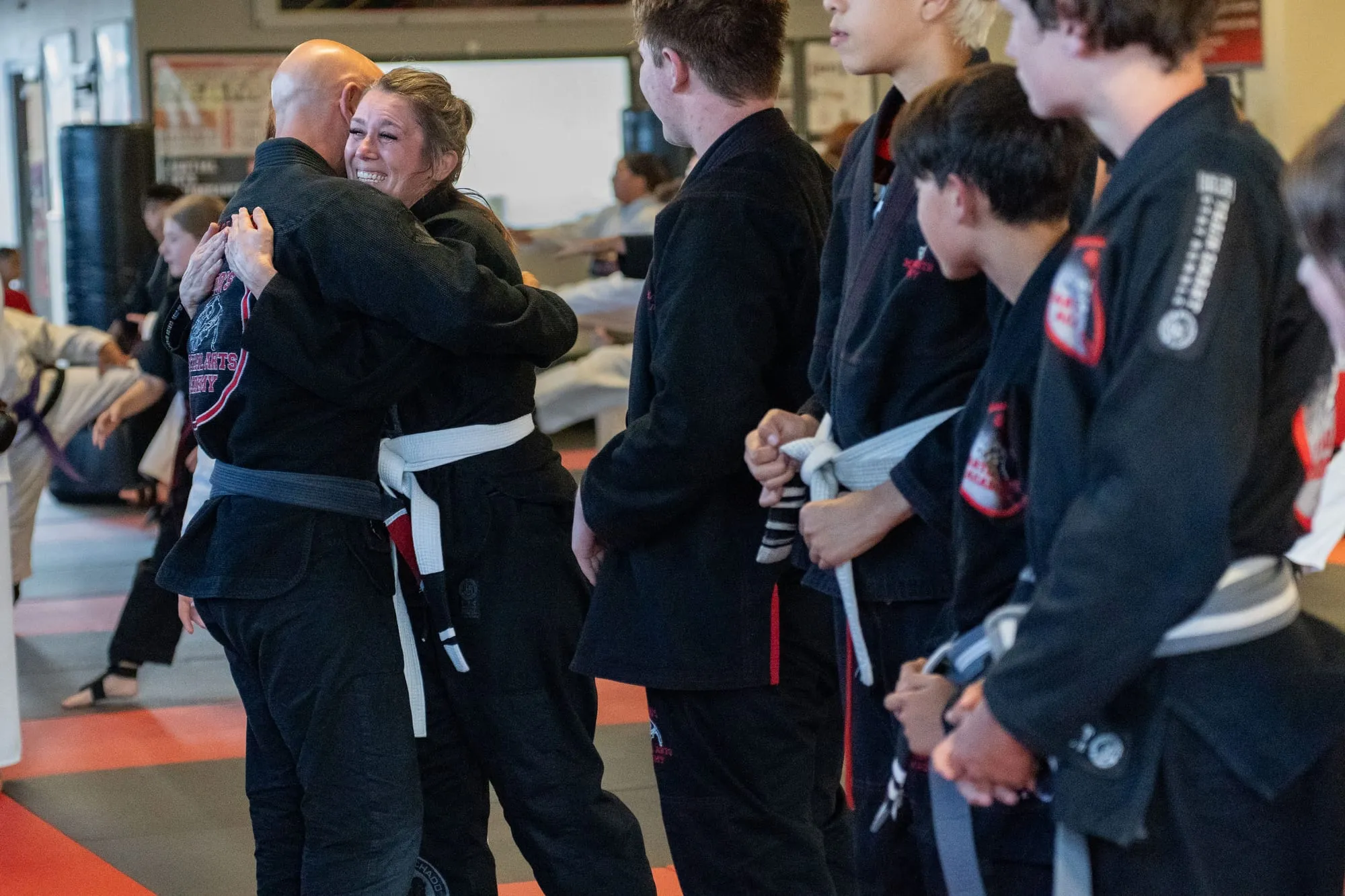Shihan Mike Guido embracing an emotional student at a belt promotion while teammates look on at Guido's Martial Arts Academy in Clovis