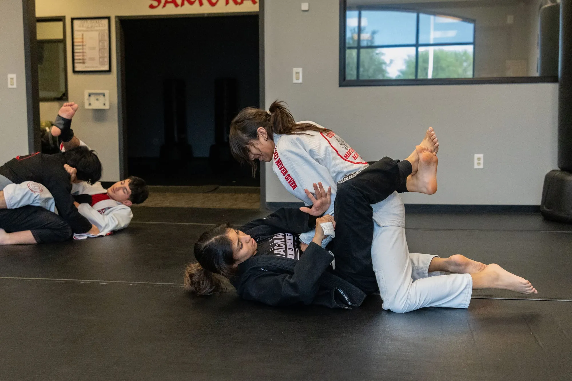 Two adult students training Brazilian Jiu-Jitsu on the mat at Guido's Martial Arts Academy in Clovis
