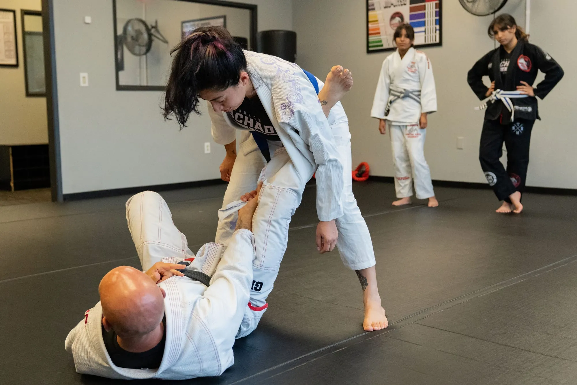 A woman practicing a Brazilian Jiu-Jitsu guard pass against a resisting partner at Guido's Martial Arts Academy in Clovis